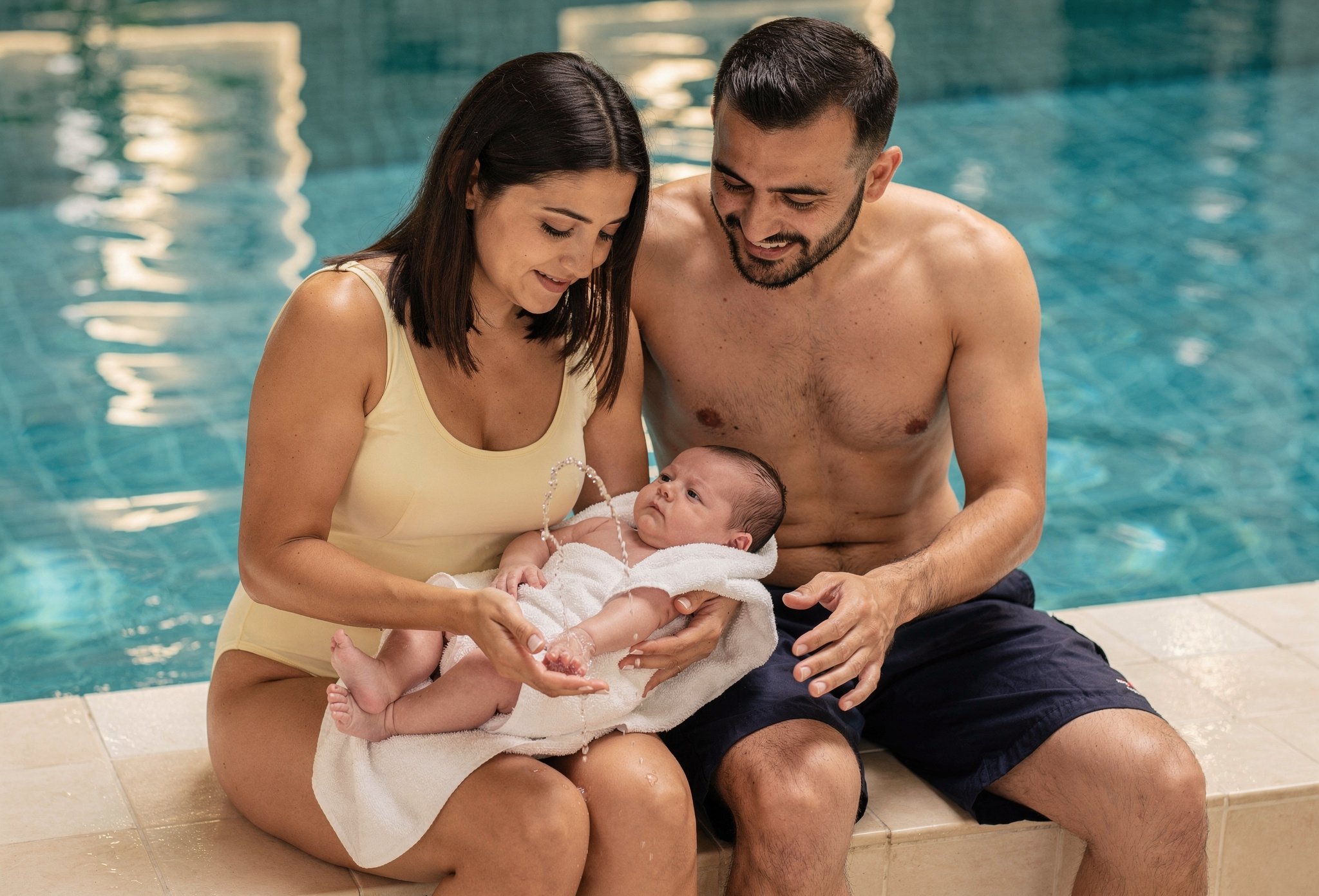 Anne ve baba bebeği ilk derse hazırlıyor havuz kenarında